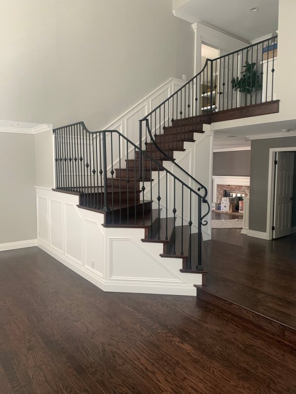 Wide staircase with dark wood treads and iron railing